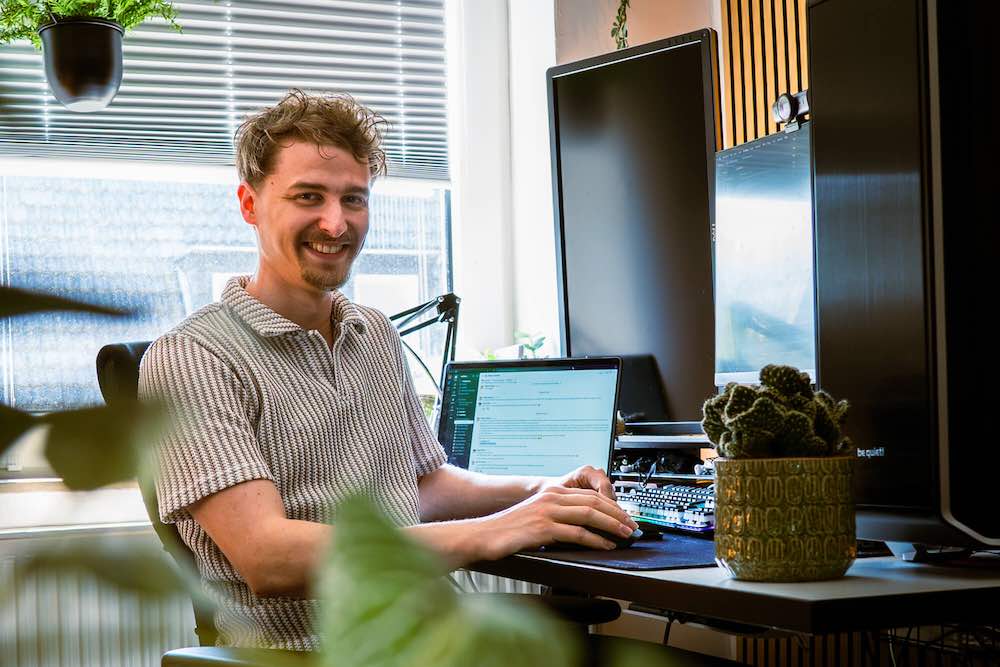 Lukas Meier sitzt an seinem Schreibtisch, umgeben von vielen Pflanzen.